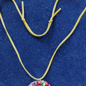 Colorful bead necklace with a round pendant on a yellow cord against a blue fabric background.